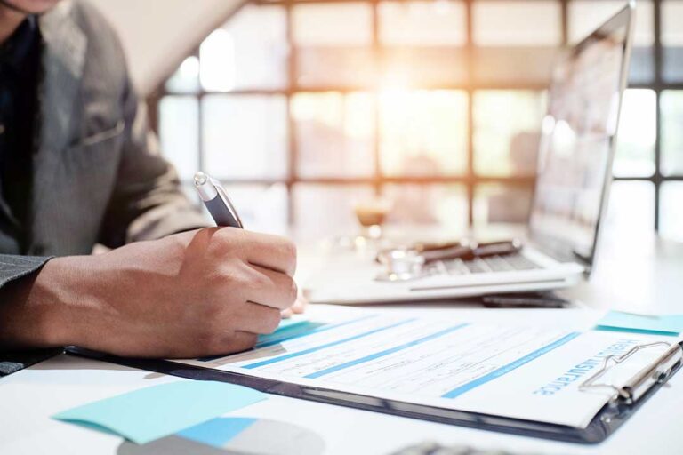 Family members review a life insurance policy and funeral documents at a kitchen table.